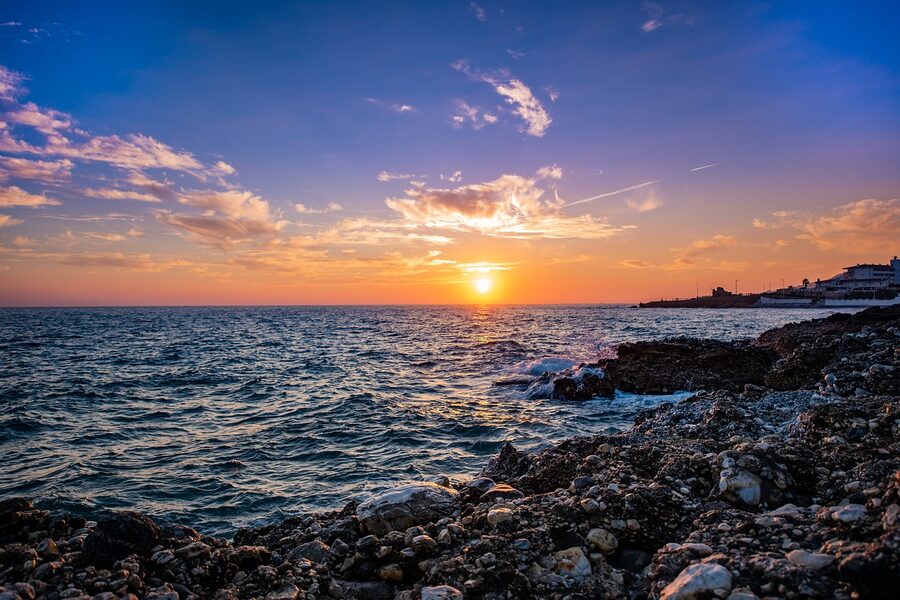 Wide sandy beach in Nerja under a sky filled with dramatic clouds and blue patches