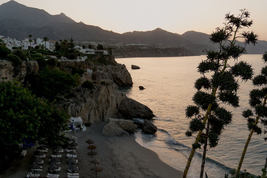 Rocky coastal cliffs near Nerja with a small sandy beach below during golden hour sunset