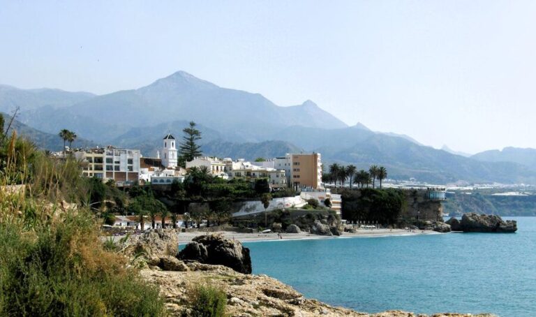 Panoramic view of the coastal town of Nerja in southern Spain with mountains behind and clear blue Mediterranean waters