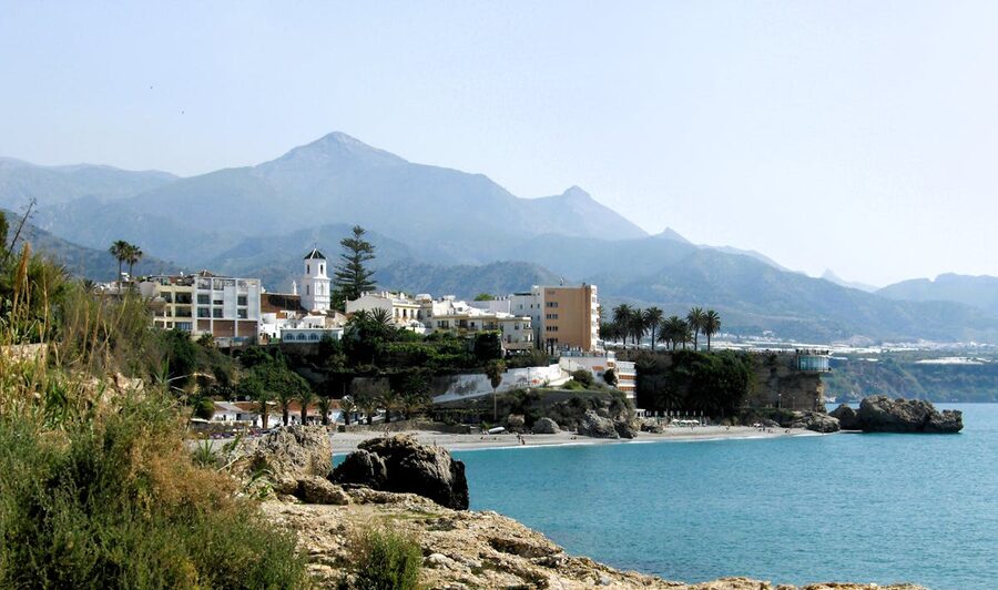 White buildings of Nerja along the coastline with mountains rising behind