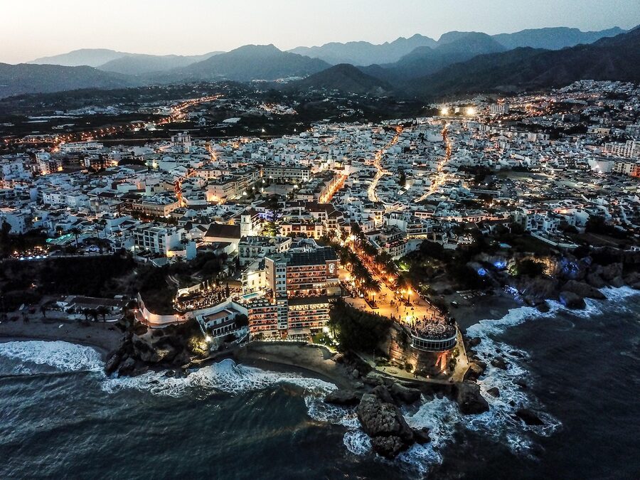 The Nerja seafront lit up at dusk with waves breaking along the coast
