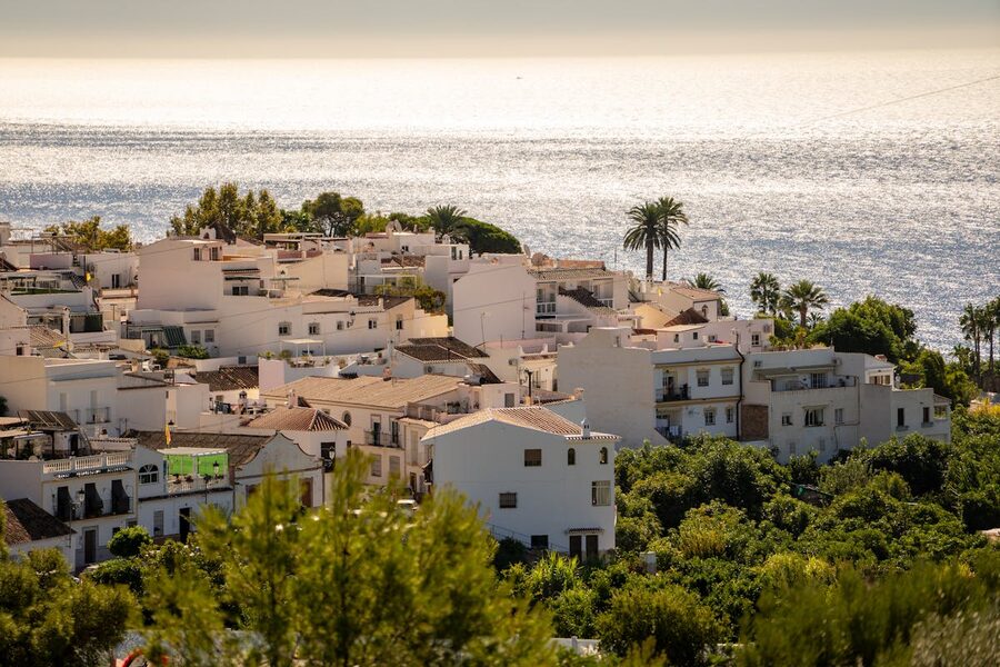 Whitewashed houses of Nerja perched above the shimmering Mediterranean Sea on a sunny day