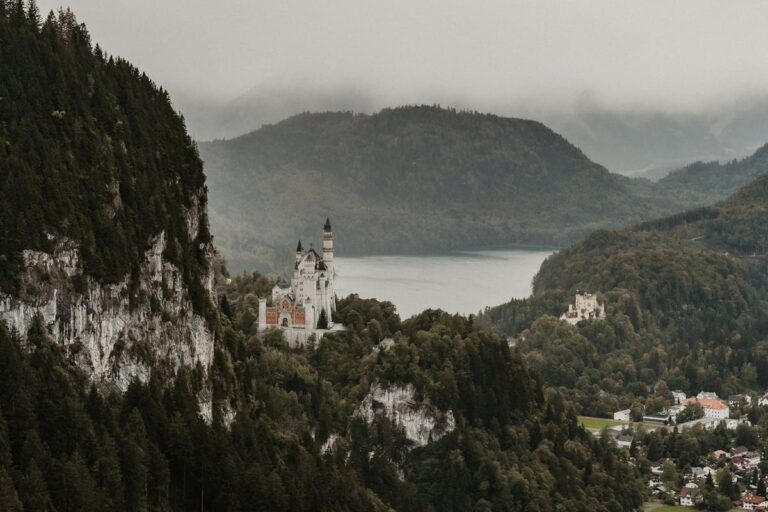 Neuschwanstein Castle rising above the Bavarian Alps with green forested hills stretching to the horizon