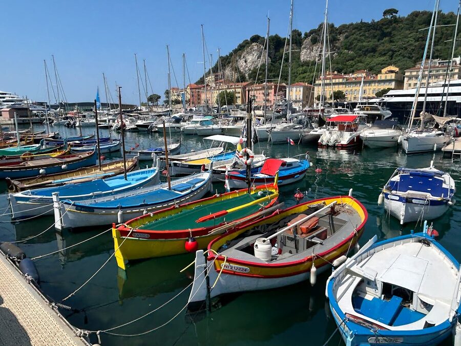 Colourful boats moored in the old harbour of Nice with coastal buildings behind