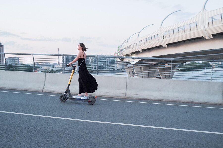 Woman riding an electric scooter along a city street