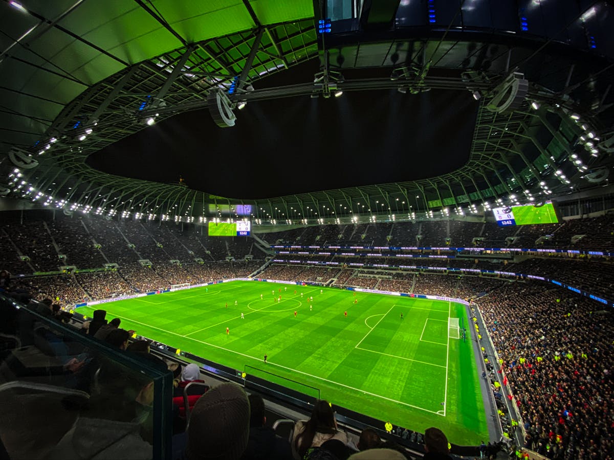 Night time football match under floodlights at a packed stadium in England