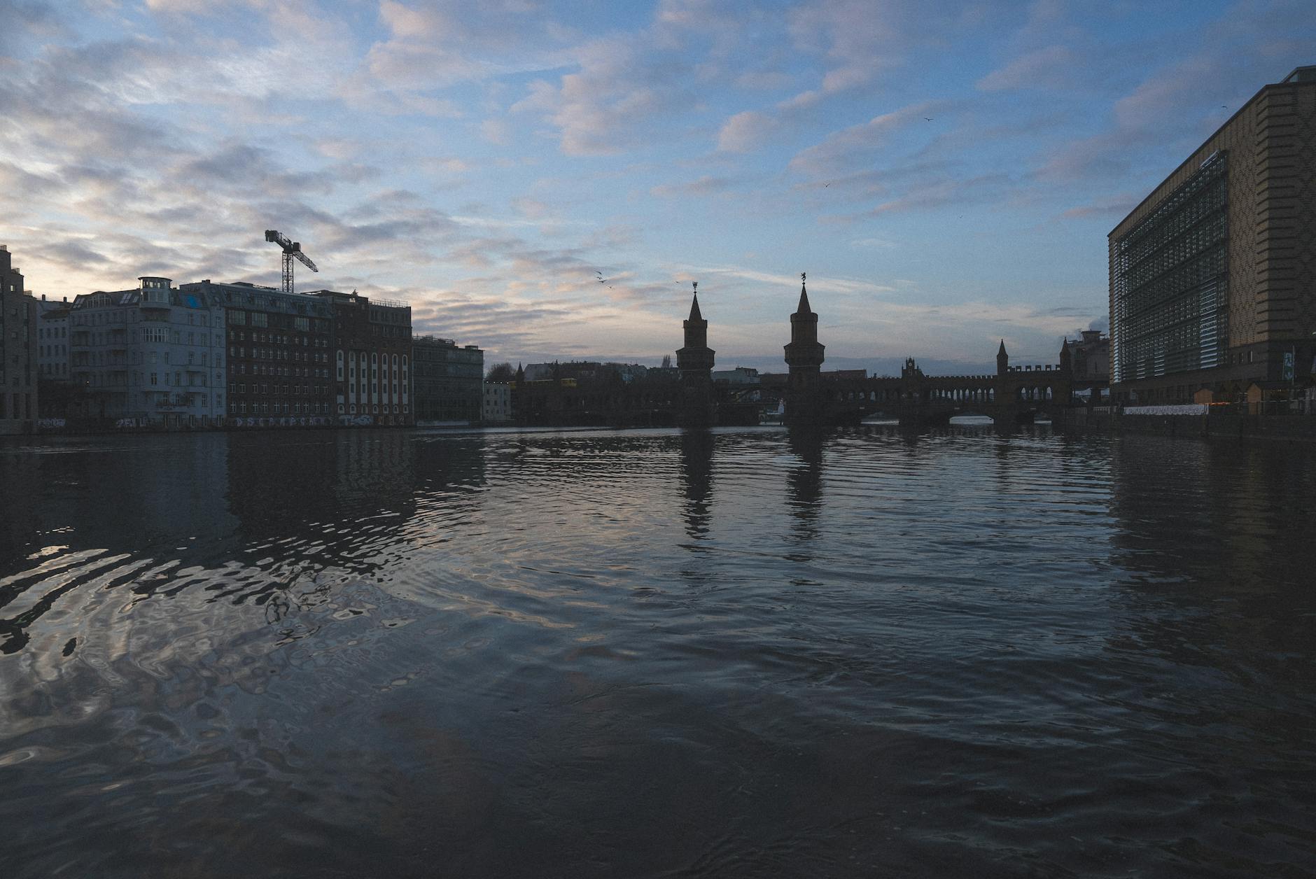 The Oberbaum Bridge silhouetted against an orange sunset over the Spree