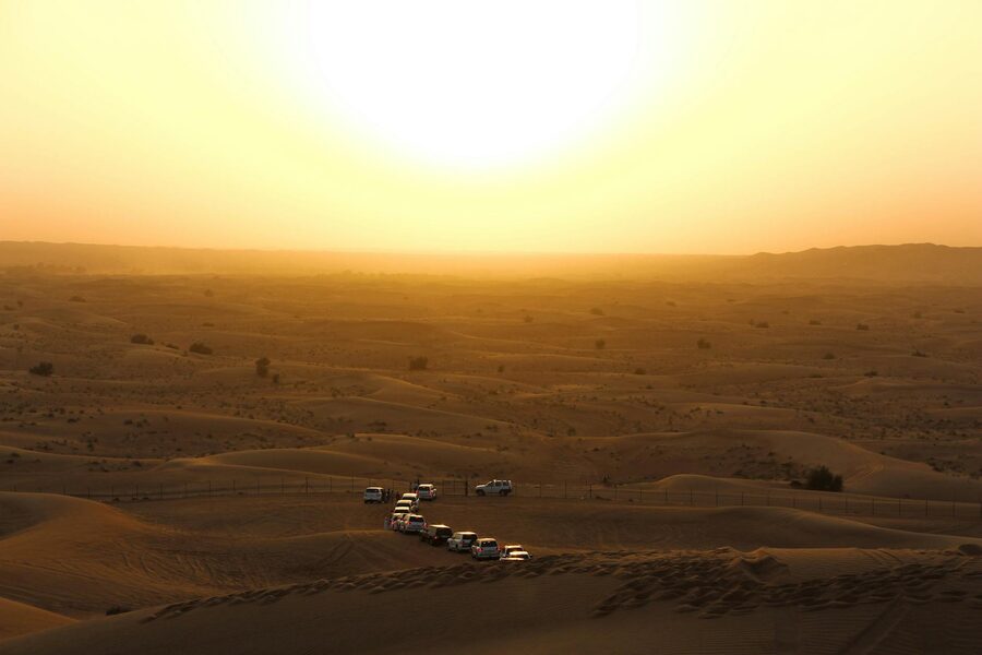 Off-road vehicles crossing desert terrain during golden sunset