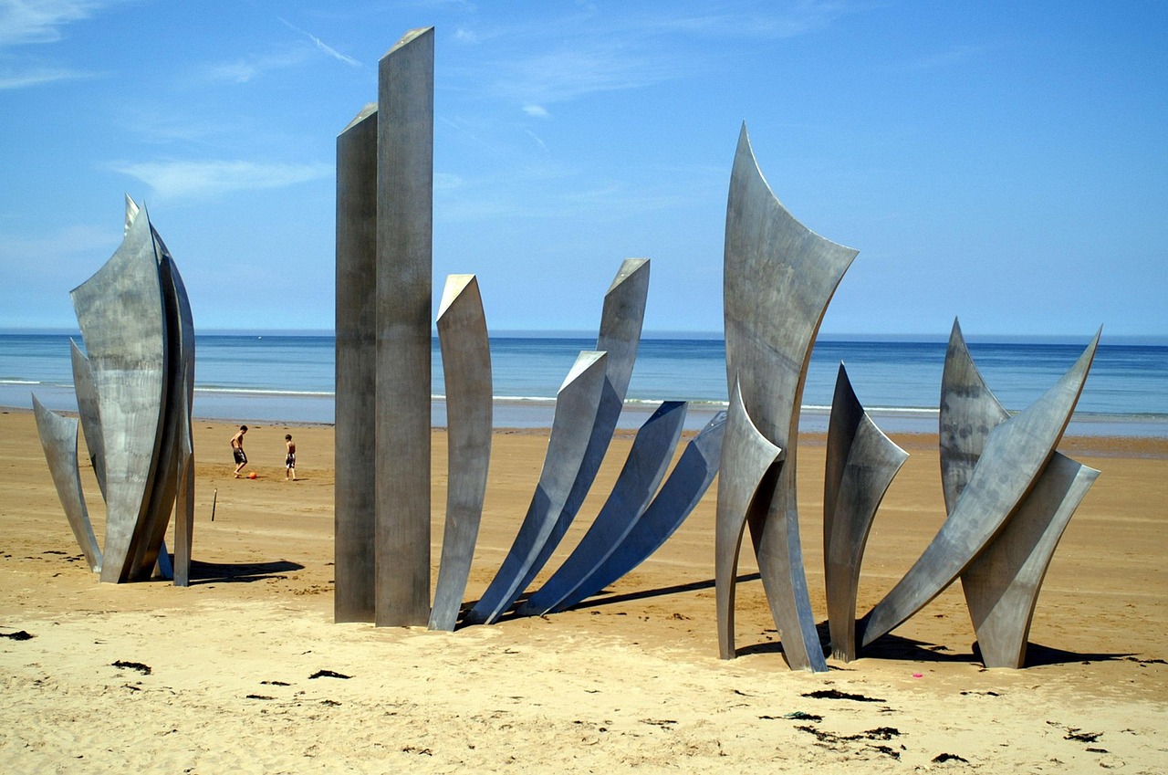 Sandy coastline of Omaha Beach with monument visible in the distance
