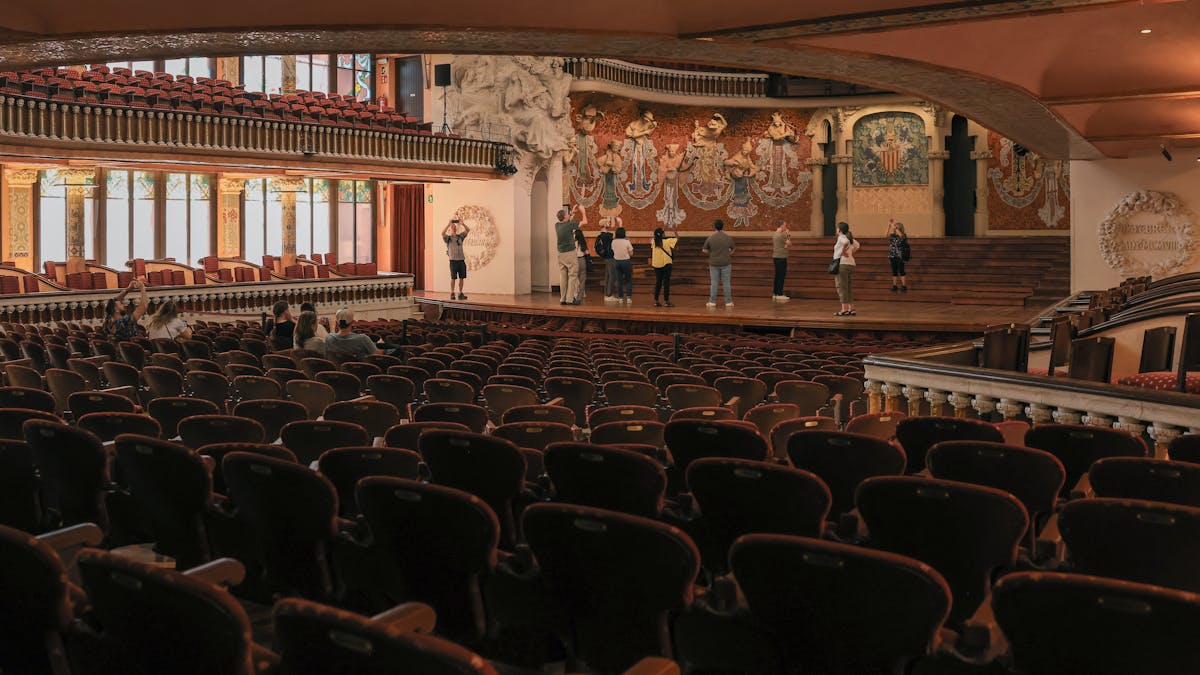 Wide view of the Palau de la Musica Catalana main concert hall showing stained glass walls and the iconic skylight