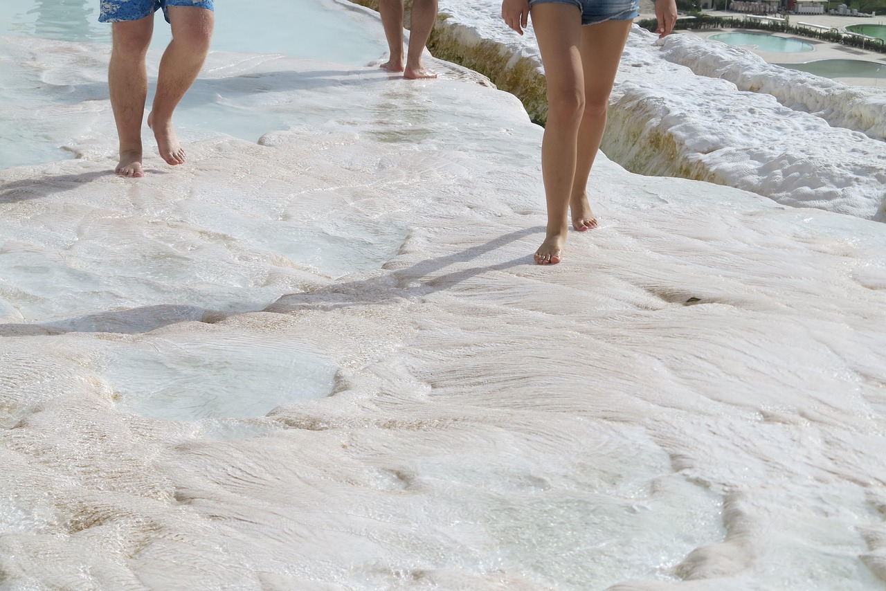 People walking on the white travertine formations at Pamukkale barefoot