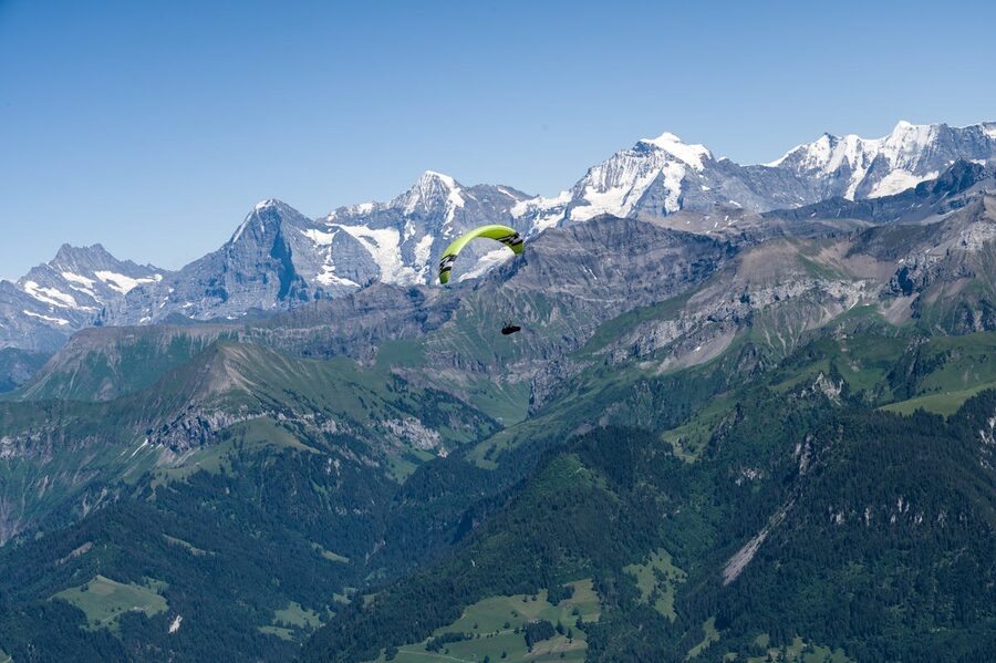 Distant paraglider soaring over panoramic Swiss Alps landscape