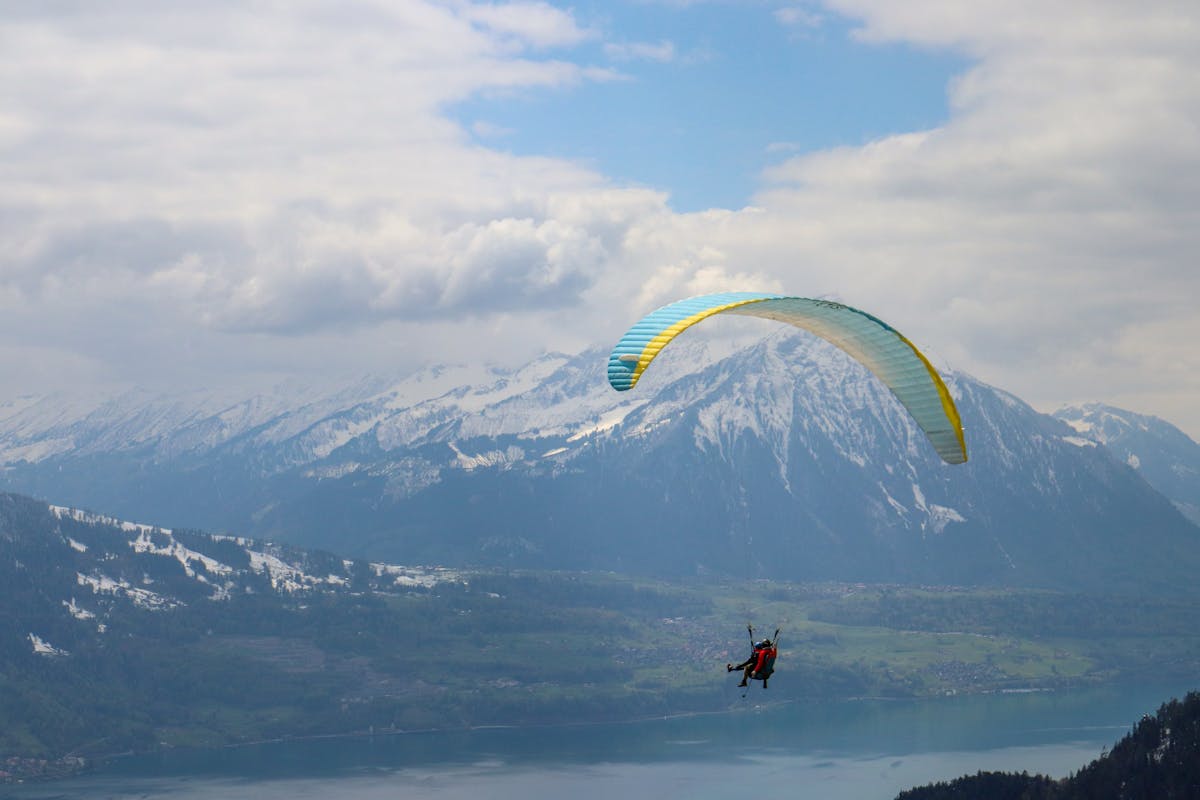 Paraglider soaring near snow-covered Swiss Alps mountains