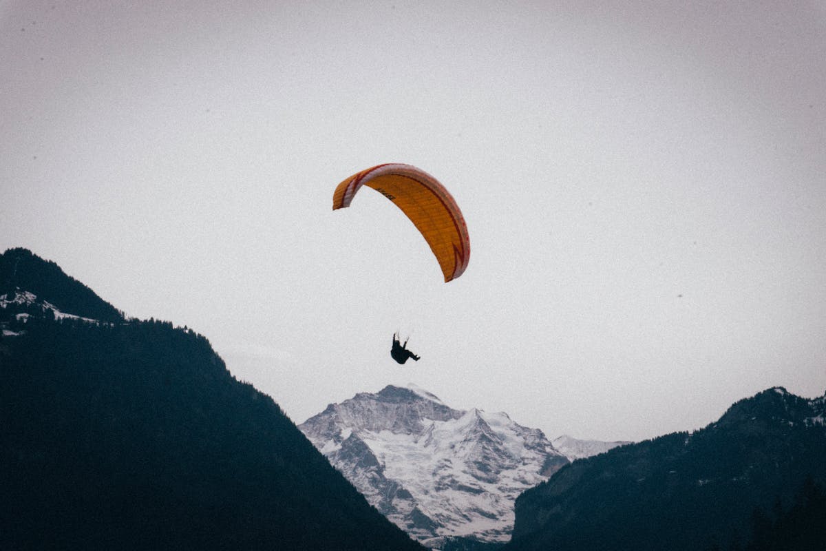 Paraglider soaring above snow-covered Swiss Alps near Interlaken
