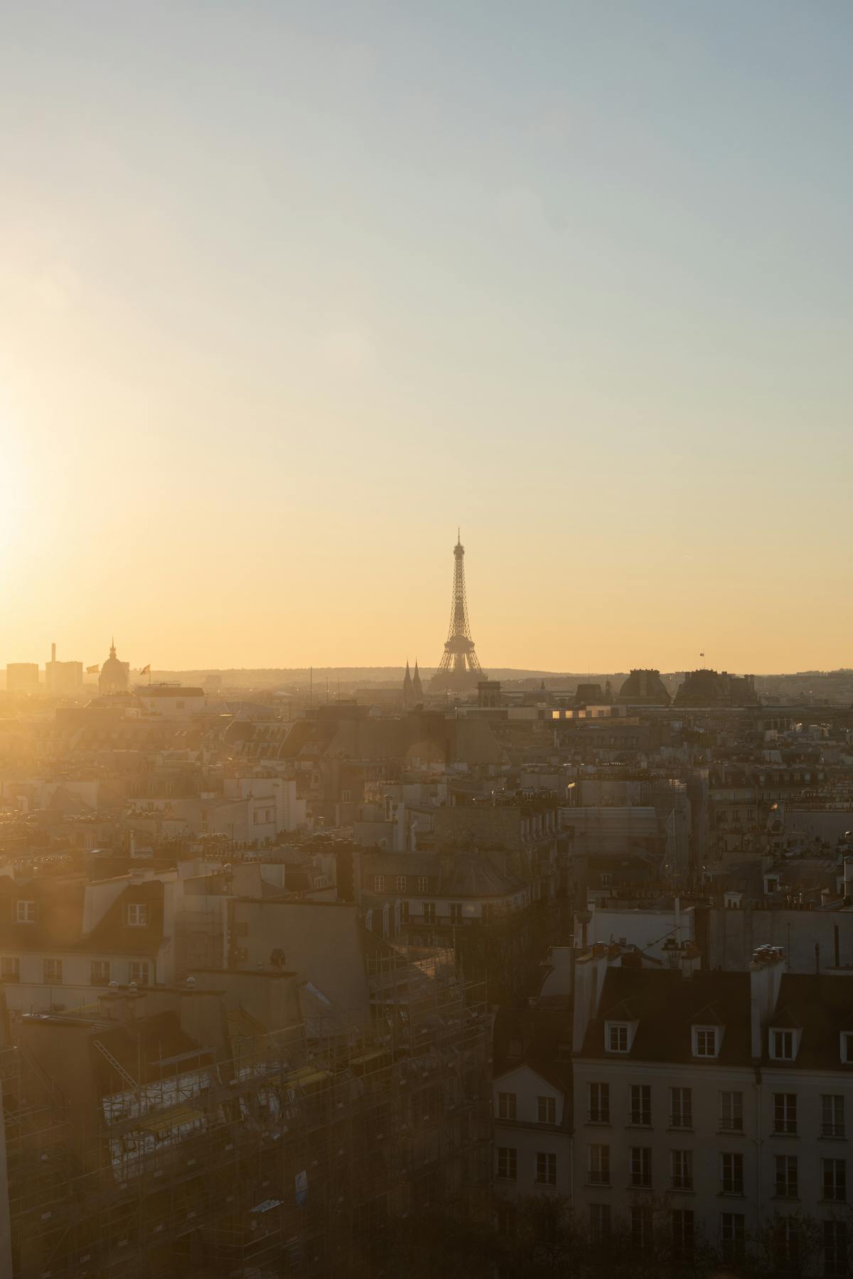 Aerial view of Paris at sunset with golden light illuminating the cityscape rooftops