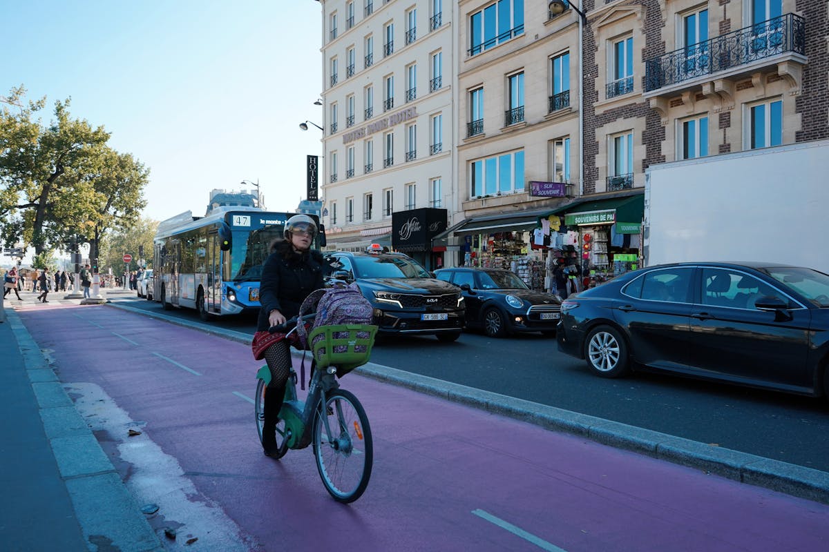 Cyclist navigating a busy Paris street with buses and cars