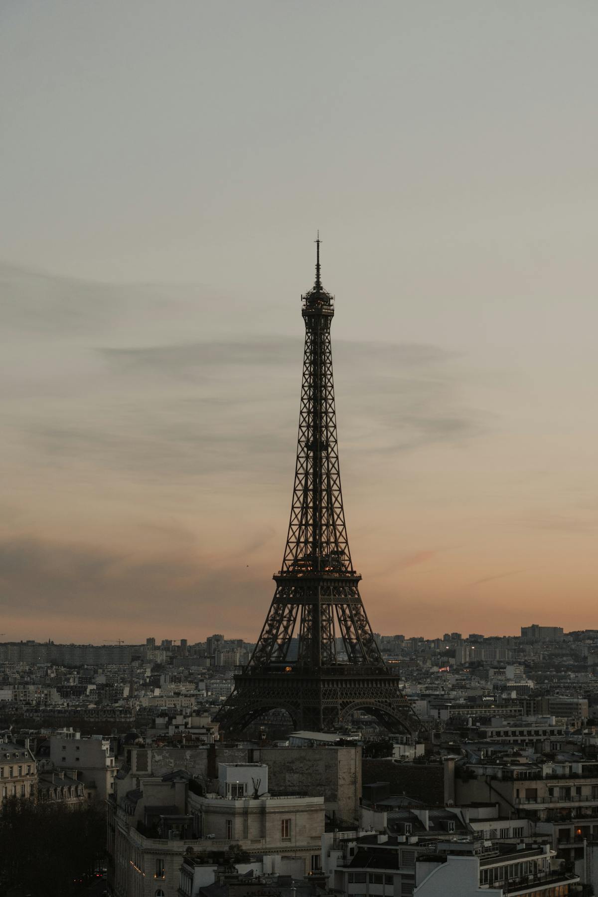 A moody sunset over Paris featuring the Eiffel Tower silhouette against golden clouds