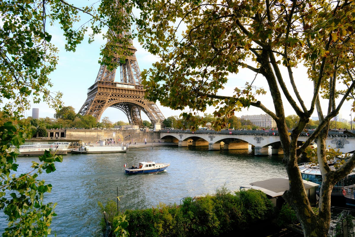 View of Eiffel Tower over Seine River with lush trees in Paris