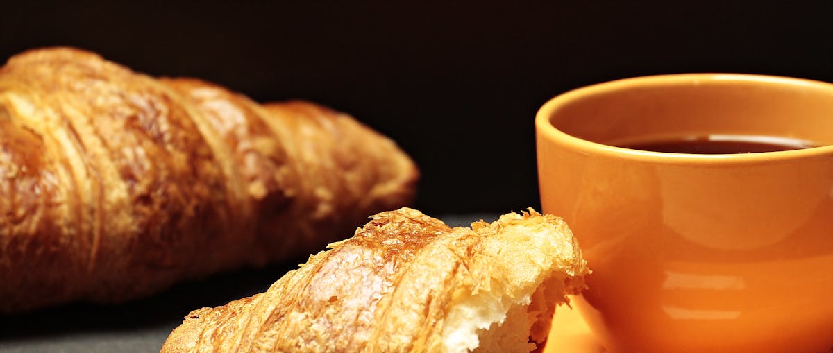 A croissant and coffee on a cafe table