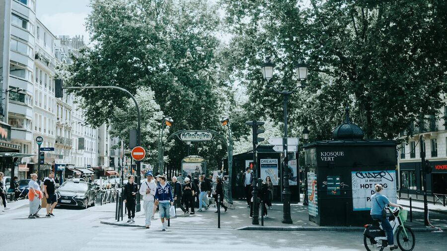 Entrance to a Paris metro station with classic signage and surrounding Haussmann buildings