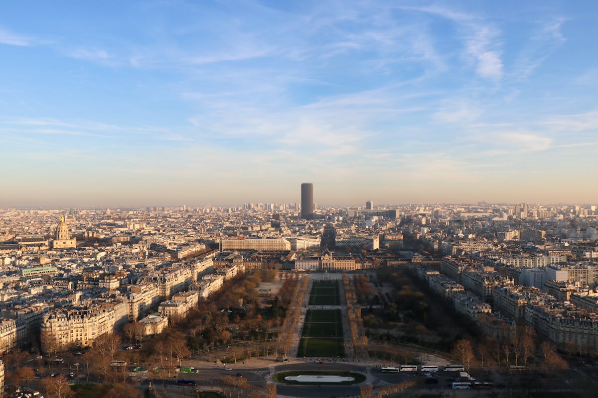 A panoramic view of the Paris cityscape at sunset with warm golden light across the rooftops