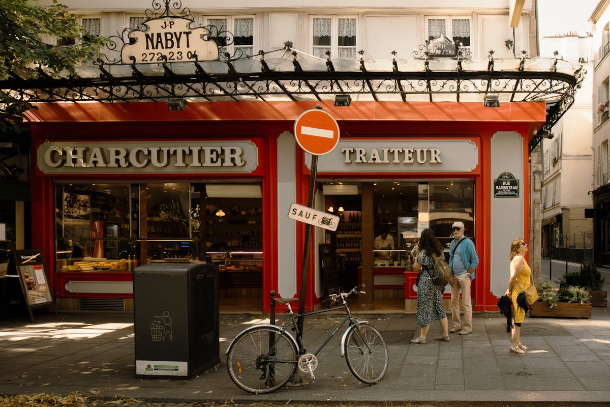 Parisian streetscape featuring a charcuterie shop and pedestrians in warm sunlight