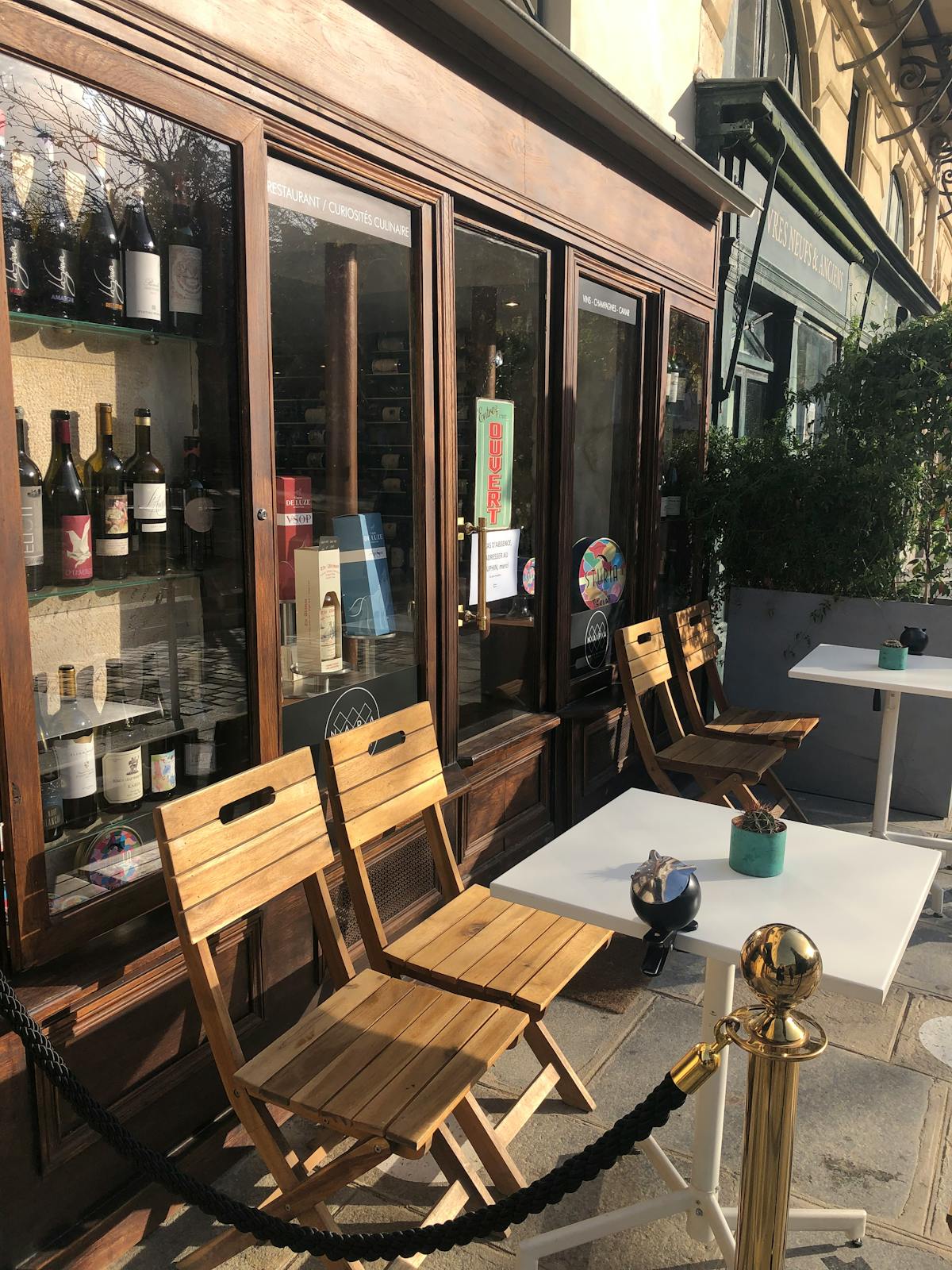 Wine bottles and sunlit patio at a Parisian cafe