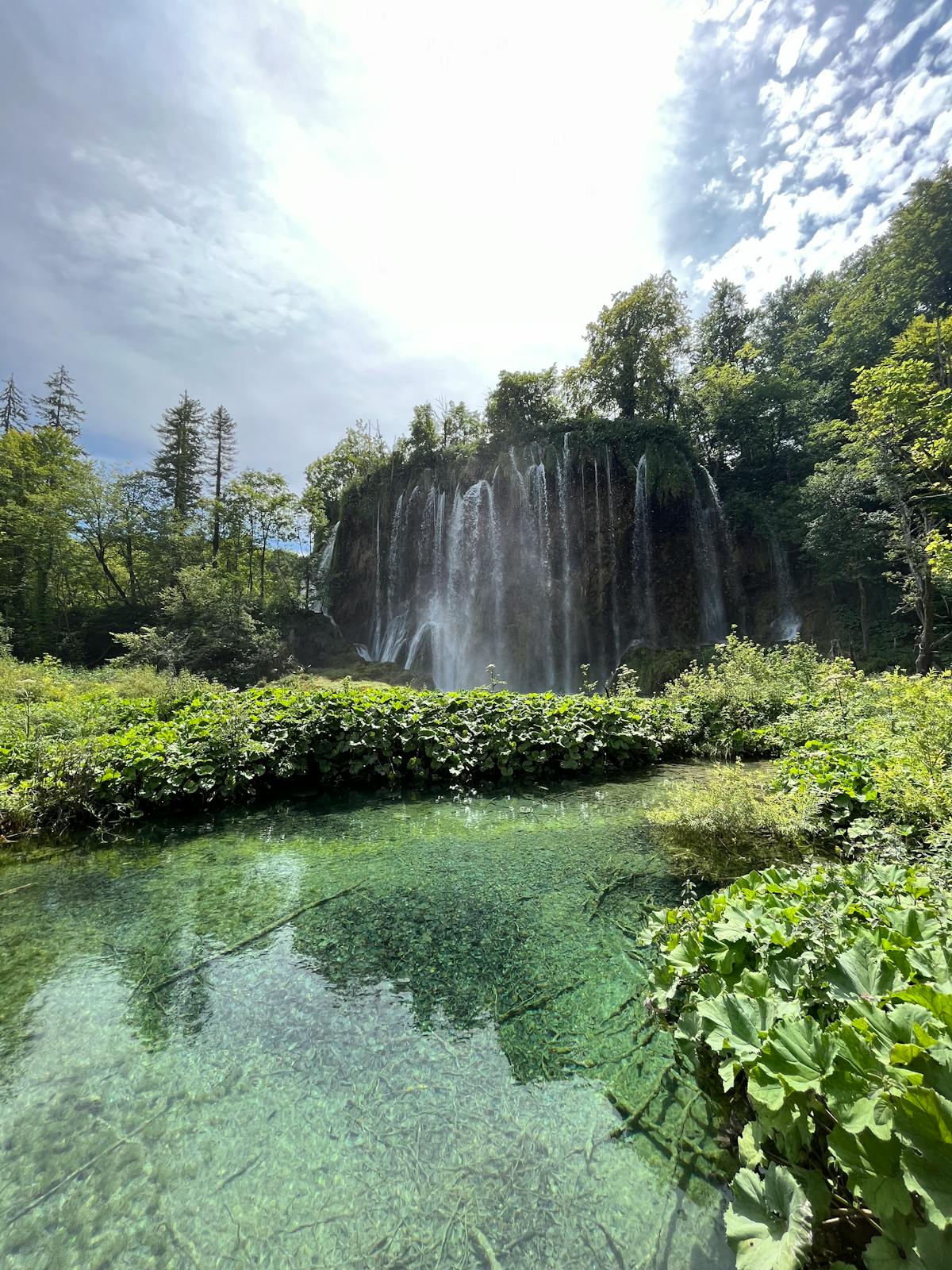 Waterfall cascading into clear pond at Plitvice Lakes
