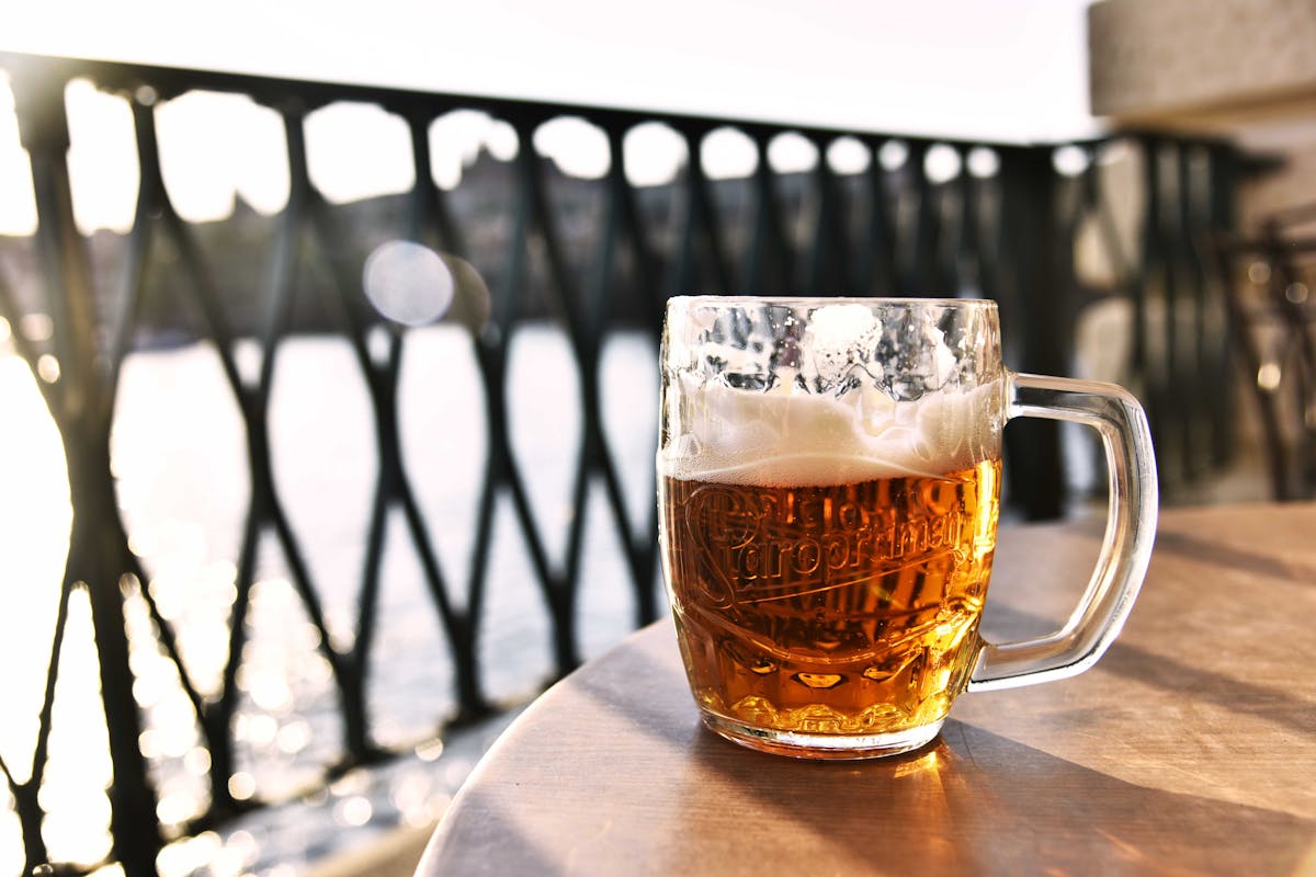 Frosty glass of Czech lager beer with Prague river view in background