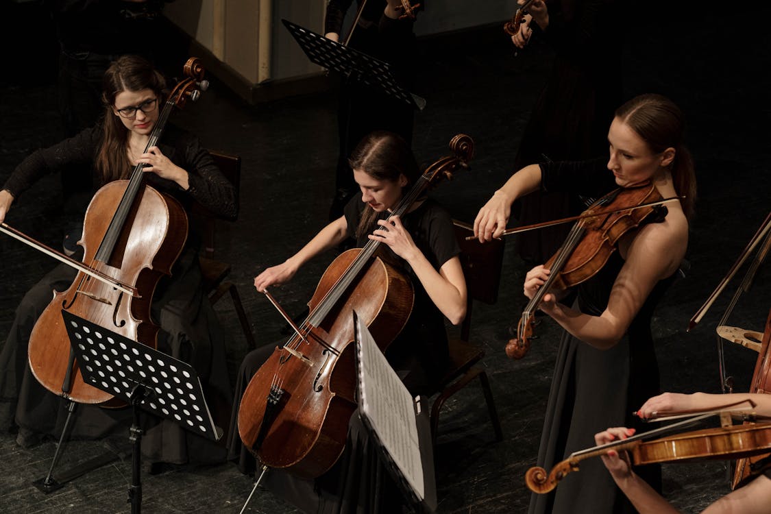 Women musicians playing cellos and violins in an orchestra