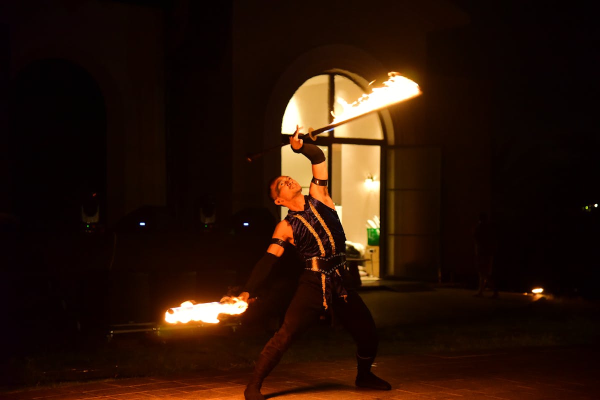 Fire dancer performing with spinning flames in a dark nighttime setting
