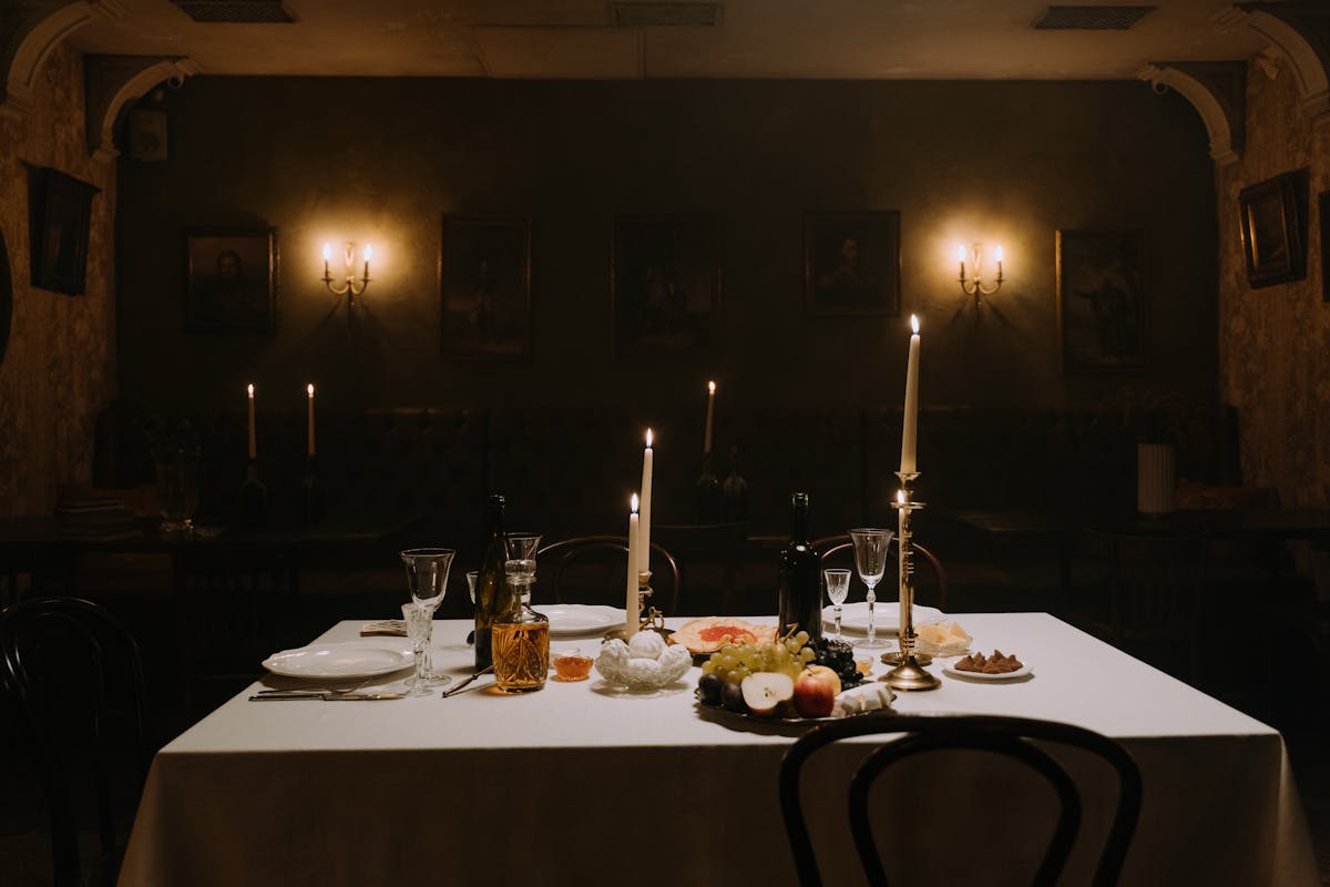 Long wooden table with candles, wine goblets, and fruit in a dimly lit medieval dining room