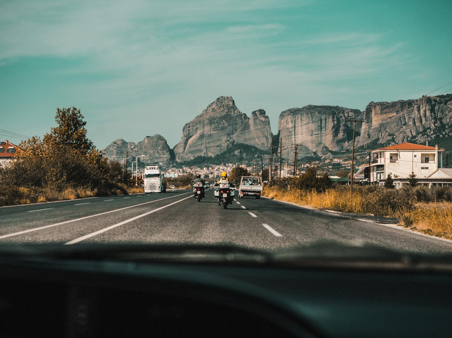 Motorcycles driving on an open road towards Meteora iconic rock formations in Greece