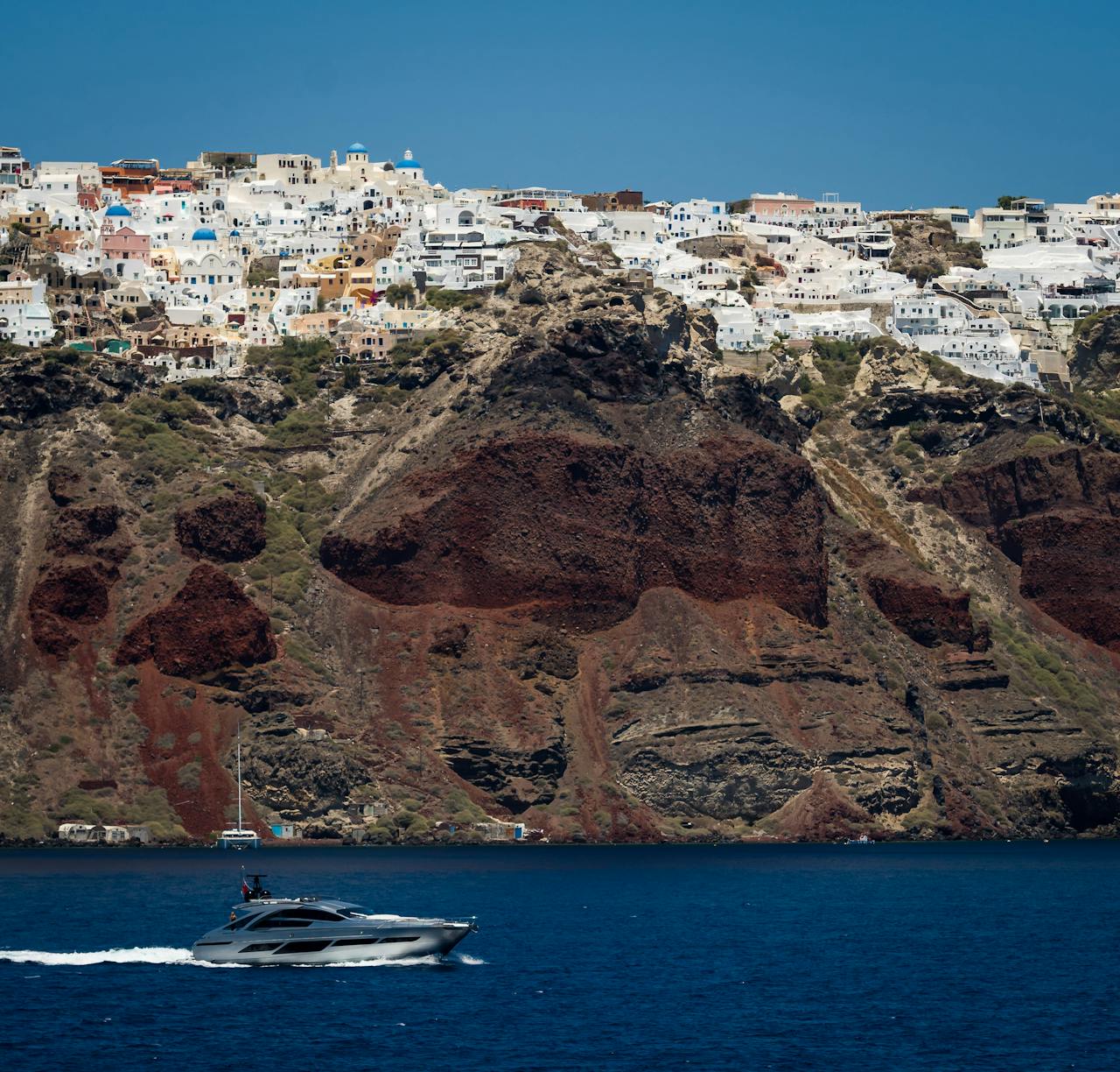 Yacht sailing below the towering cliffs of Santorini