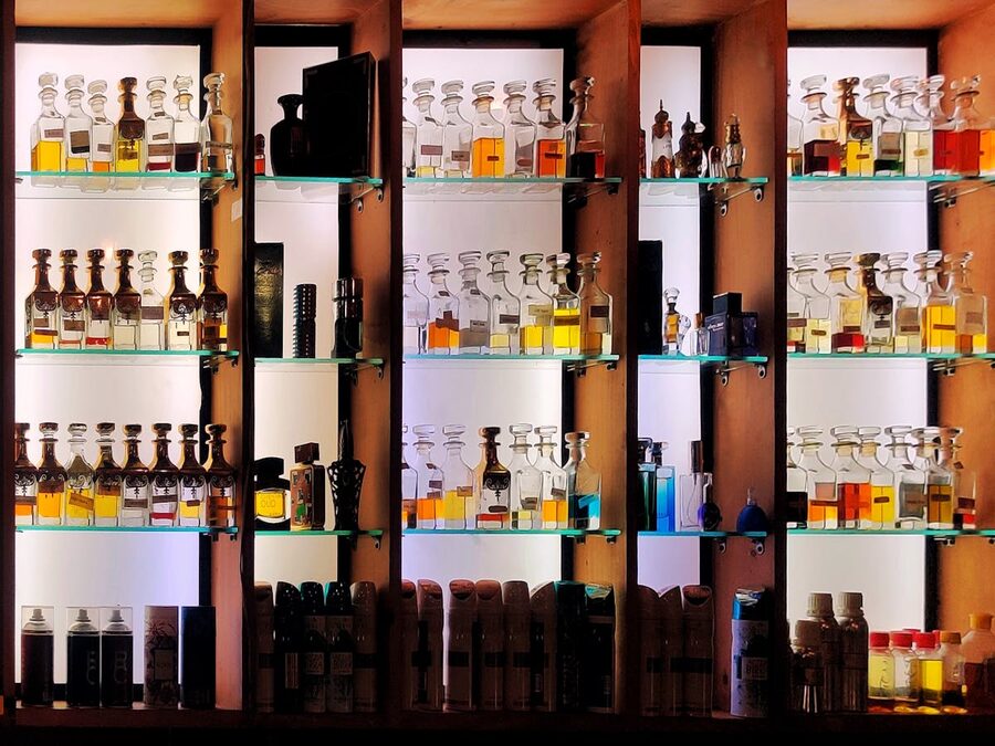 Various perfume bottles arranged on glass shelves with wood accents