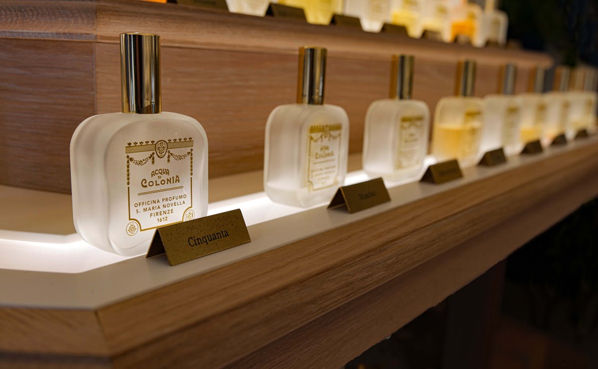 Rows of glass perfume bottles on wooden shelves in a perfumery