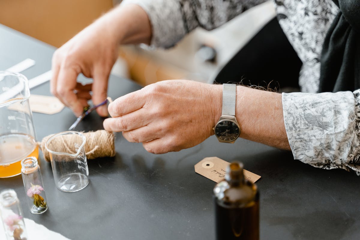 Close-up of hands crafting custom perfume scents with glass bottles and natural ingredients