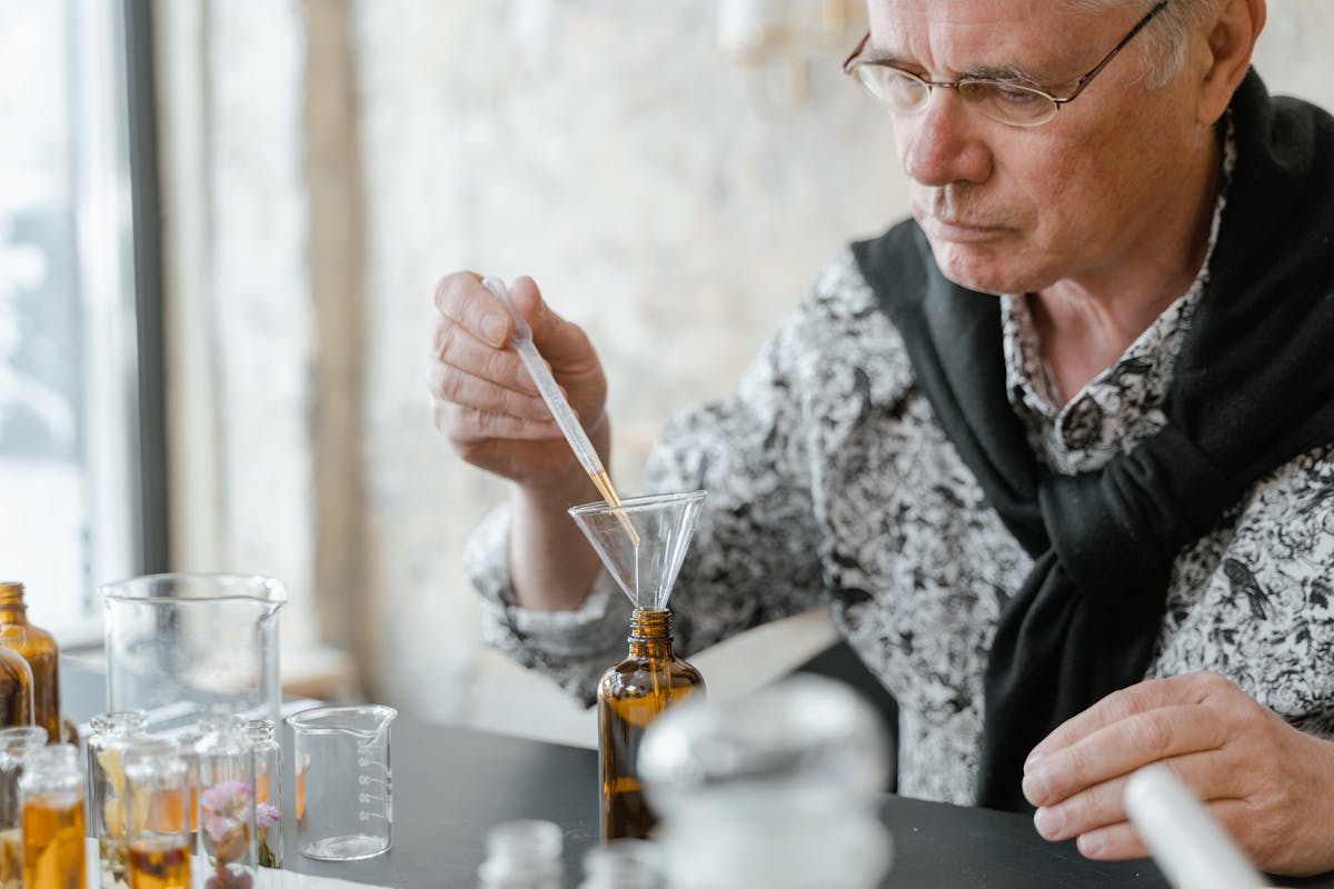 Perfumer carefully using a dropper to blend essential oils in glass bottles
