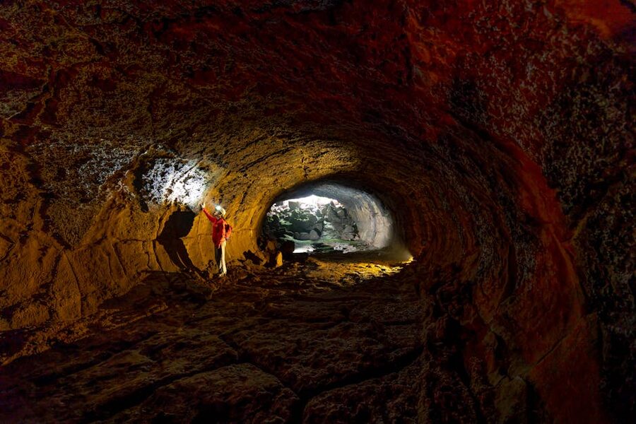 Person exploring rugged cave with flashlight