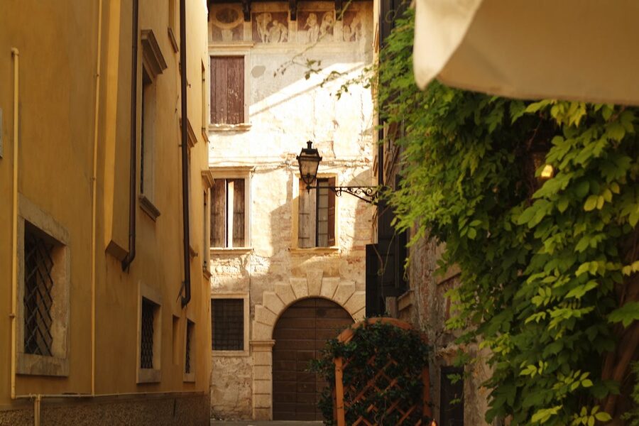 Sunlit narrow alleyway between historic stone buildings in Verona Italy