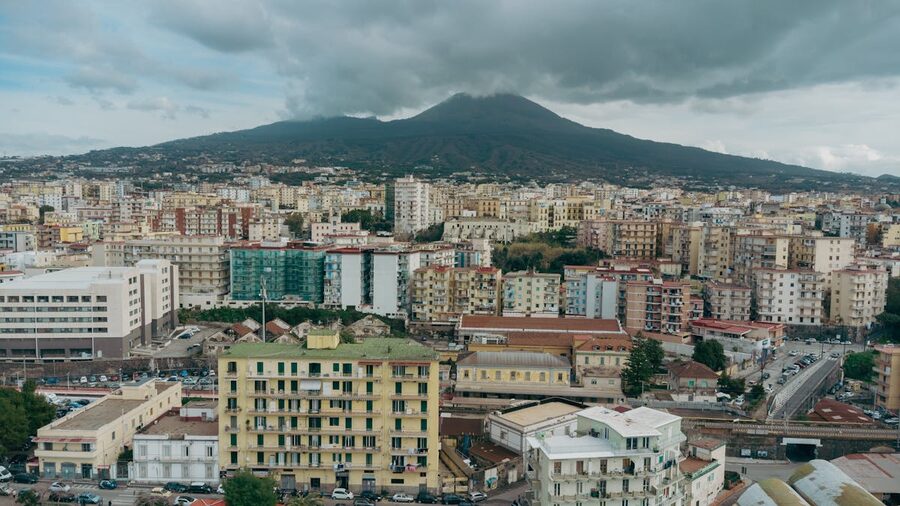 Aerial view of Naples cityscape with Mount Vesuvius under cloudy sky