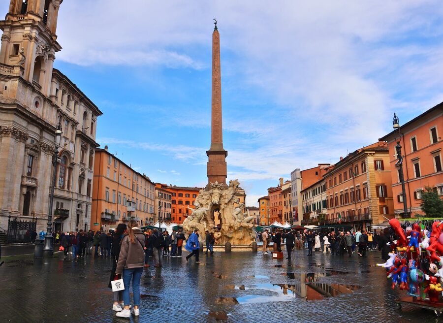 Tourists walking through Piazza Navona with the Fountain of the Four Rivers
