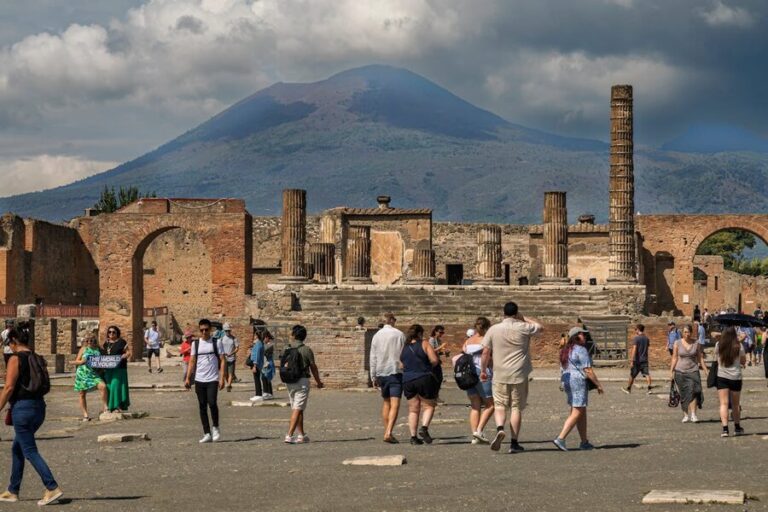 Tourists at ancient Pompeii ruins with Mount Vesuvius in the background