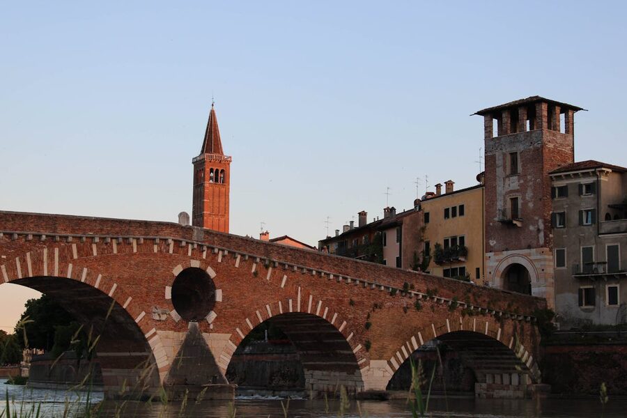 The ancient Ponte Pietra stone bridge over the Adige River at sunset in Verona