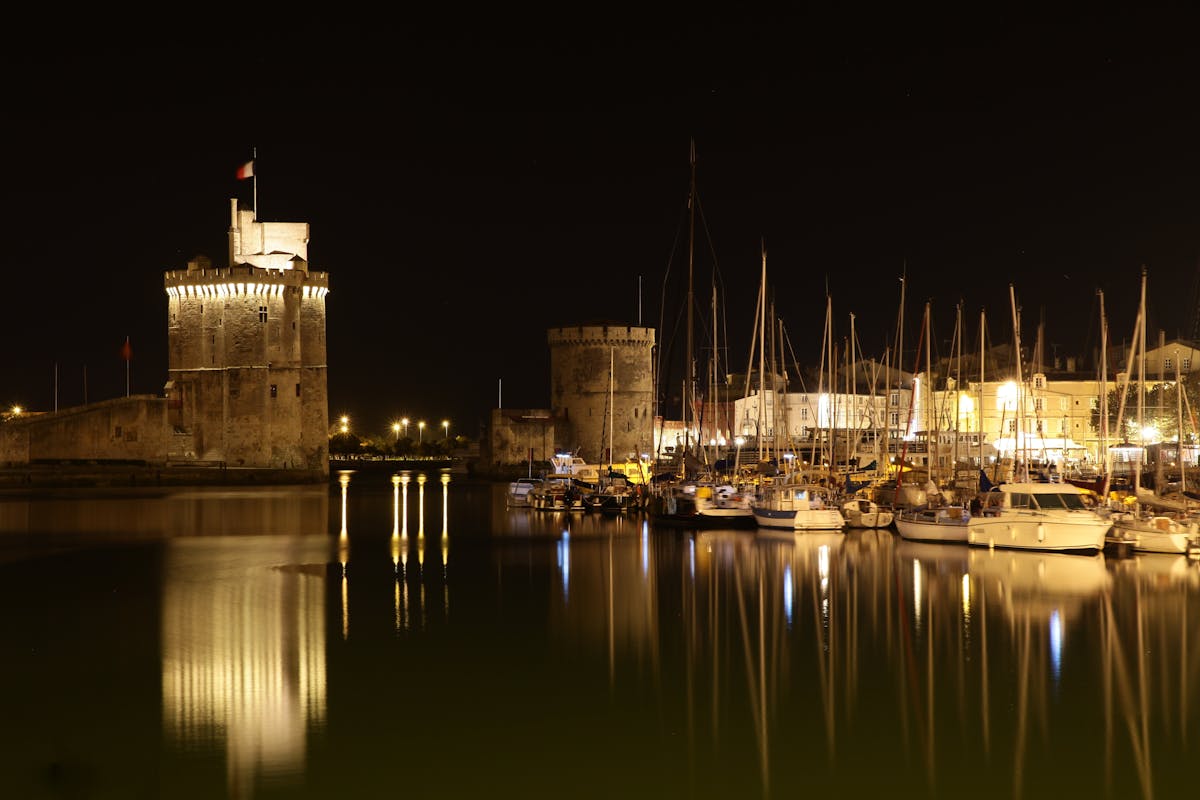 La Rochelle harbour at night with illuminated historic towers reflected in the water