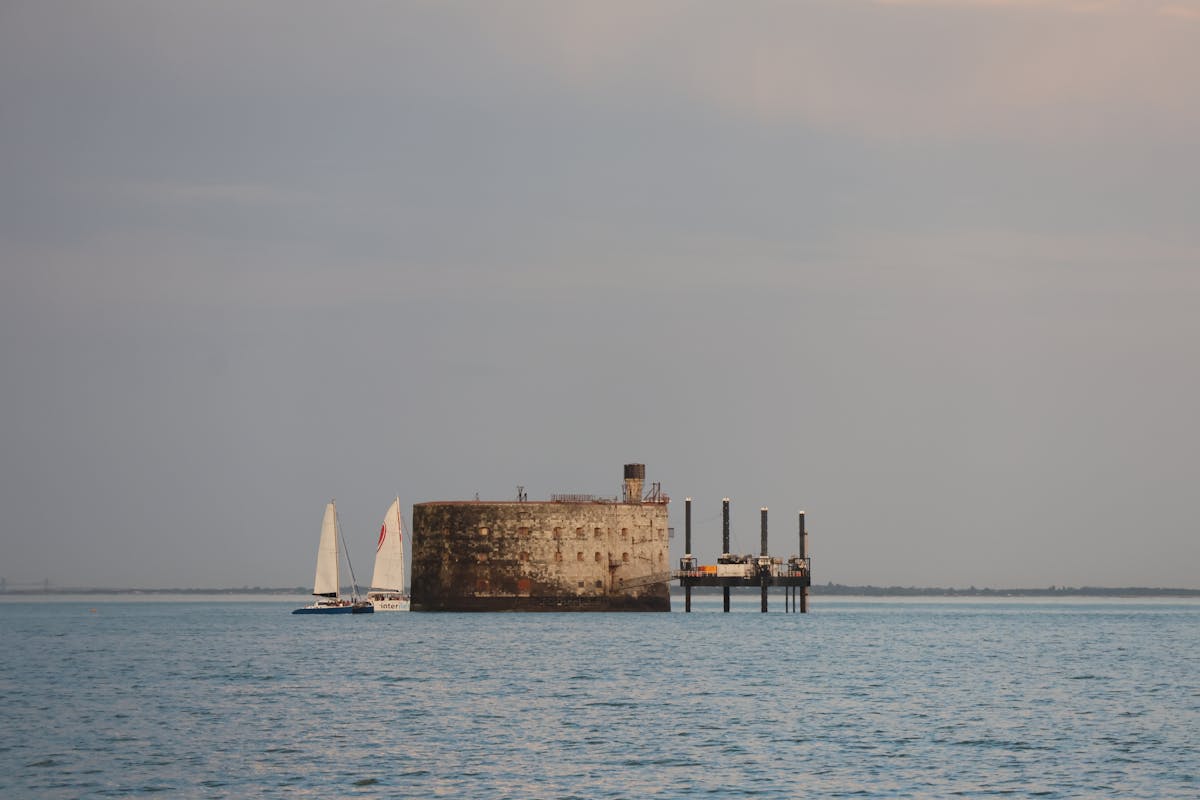Sailboats on calm waters beside Fort Boyard under a blue sky