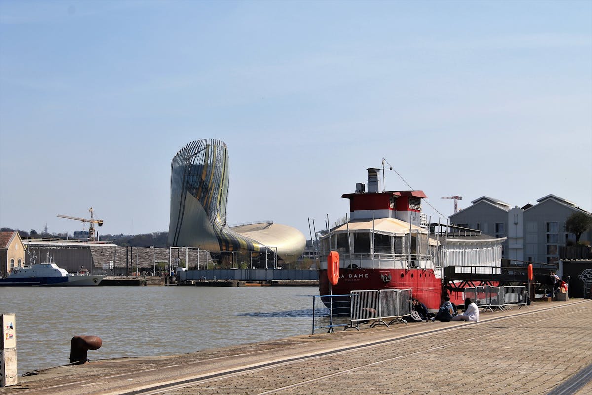 A classic ferry boat in Bordeaux harbor with modern architecture in the background