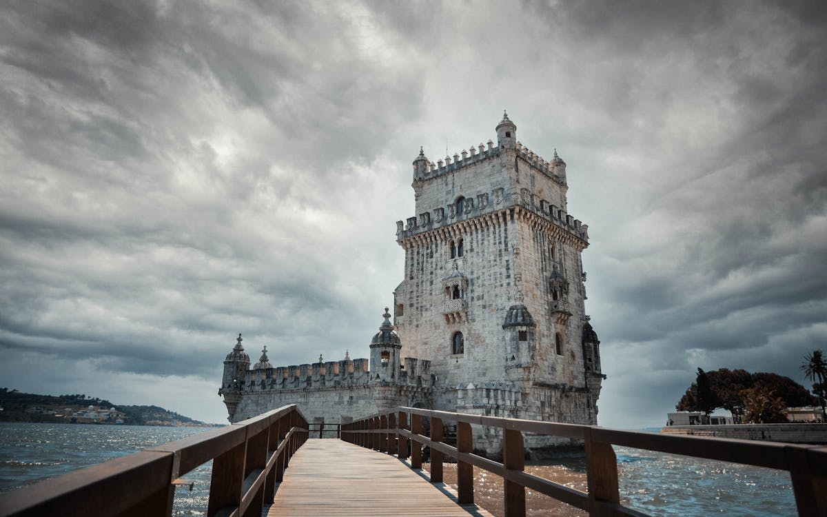 The iconic Belem Tower under a dramatic sky over the Tagus River in Lisbon