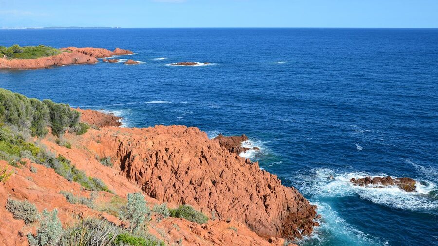 Red volcanic cliffs of the Esterel coast meeting the turquoise Mediterranean sea