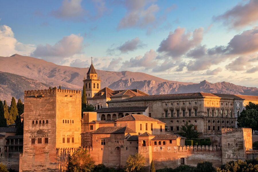 The Alhambra Palace bathed in warm golden light with the Sierra Nevada mountains visible behind